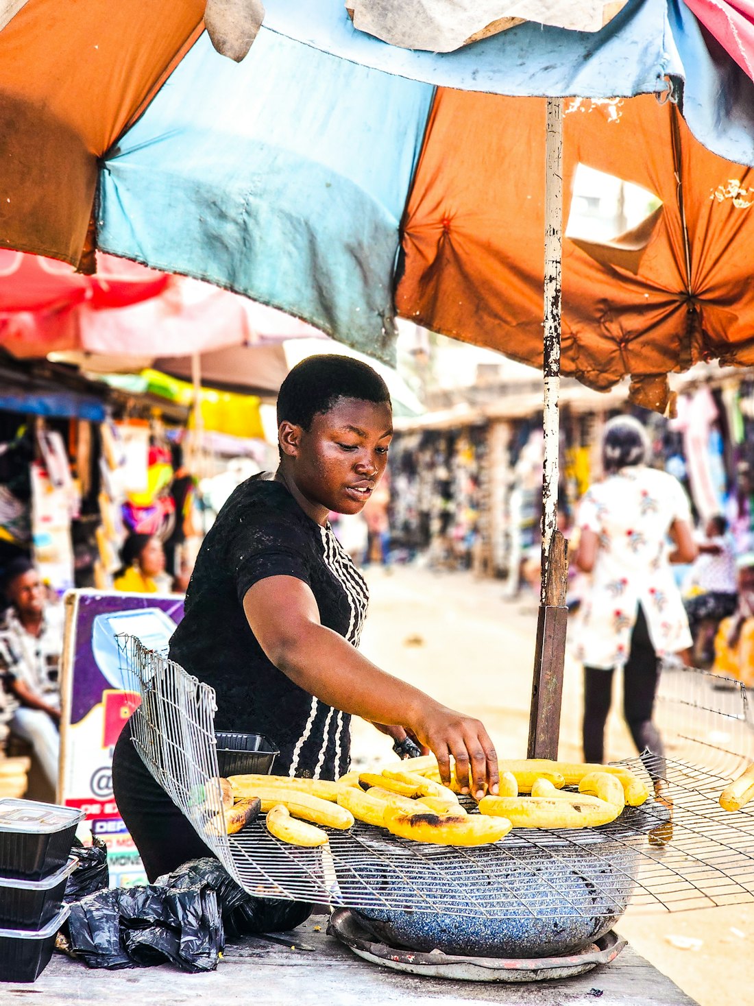 A trader roasting plantain at her market stall