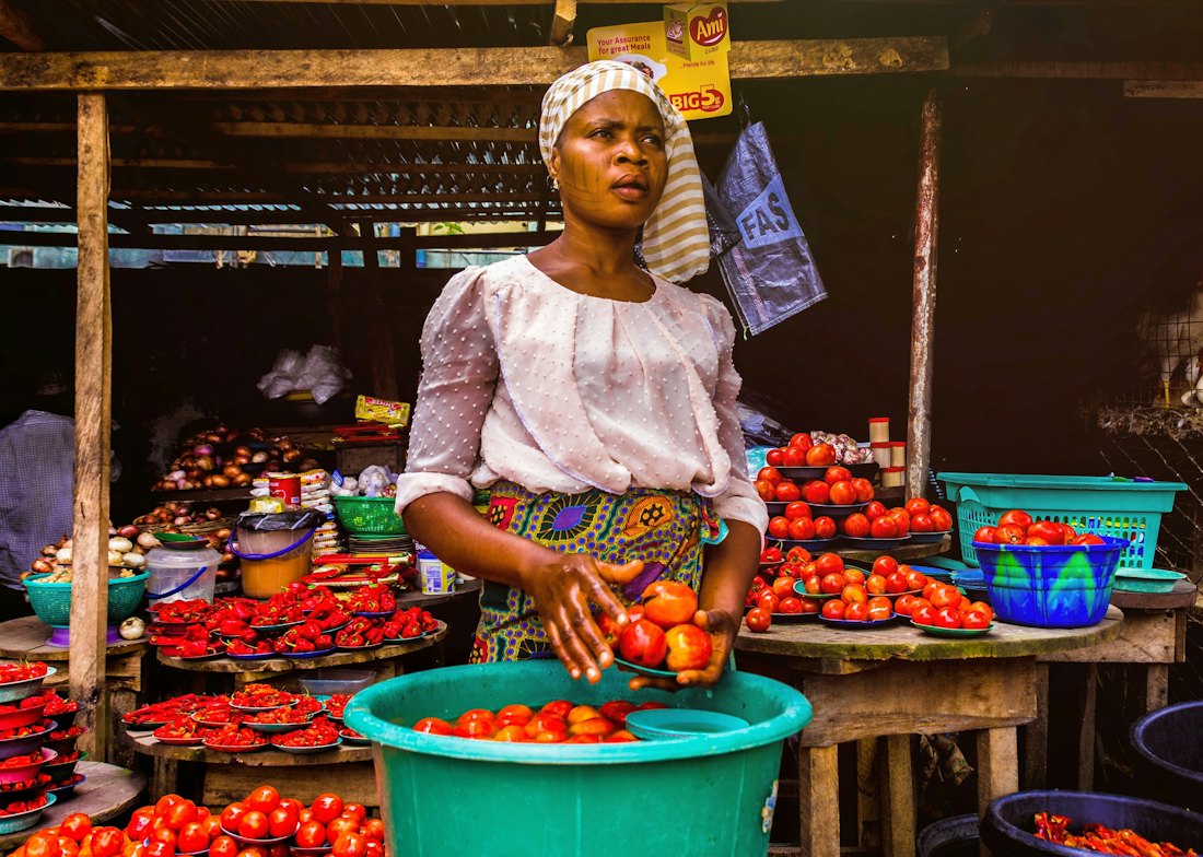 A trader arranging tomatoes at her market stall