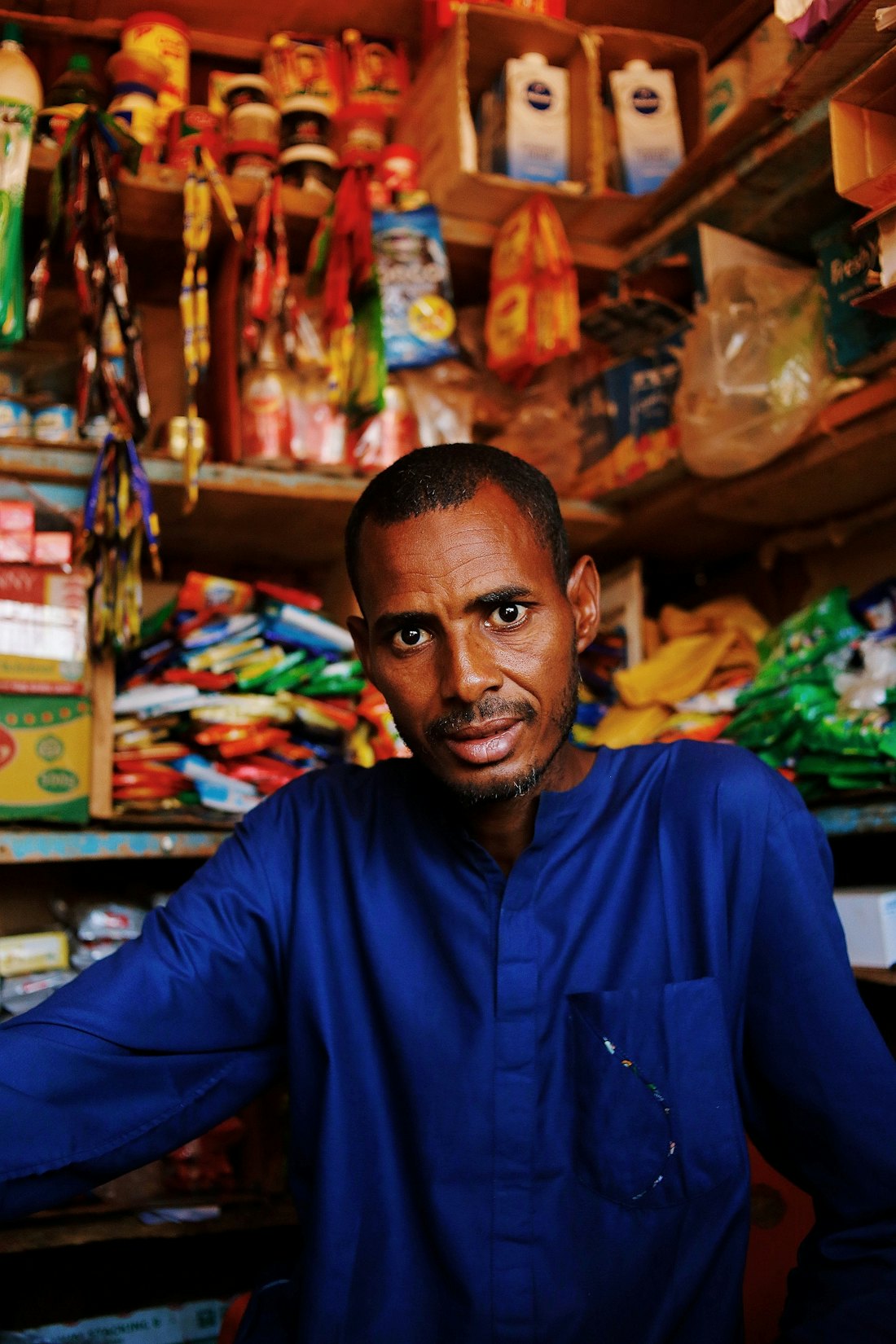 A shop owner standing at the counter of his provisions store